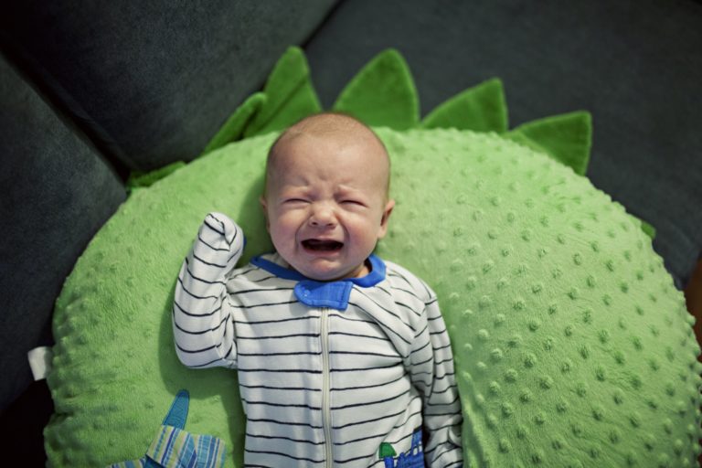 baby crying on a green pillow
