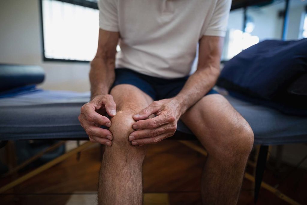 Gonartrosis síntomas un hombre viejo pone sus manos en la rodilla de dolor