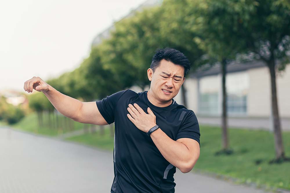bursitis de hombro ejercicios: un hombre se lleva la mano en el hombro en señal de dolor